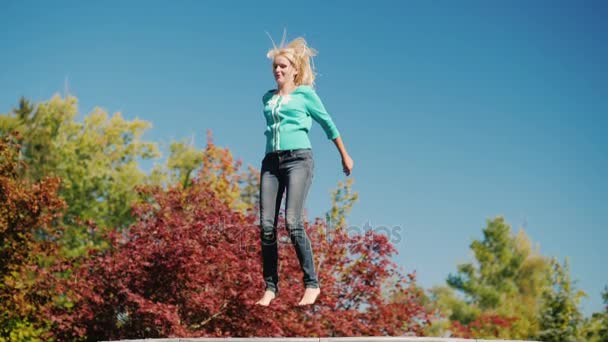En medelålders kvinna högt upp på en studsmatta. Aktiv livsstil. Slow motion video — Stockvideo