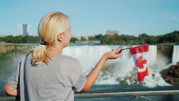 Μια γυναίκα με μια καναδική σημαία θαυμάζει Νιαγάρας (Καταρράκτες) — Αρχείο Βίντεο