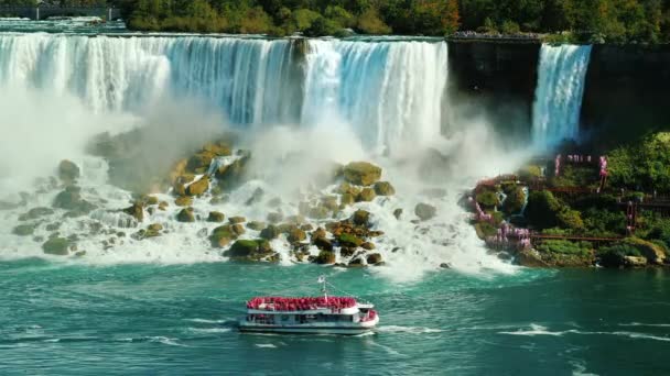 Ett fartyg med turister seglar under berömda Niagarafallen. Visa från den kanadensiska kusten — Stockvideo