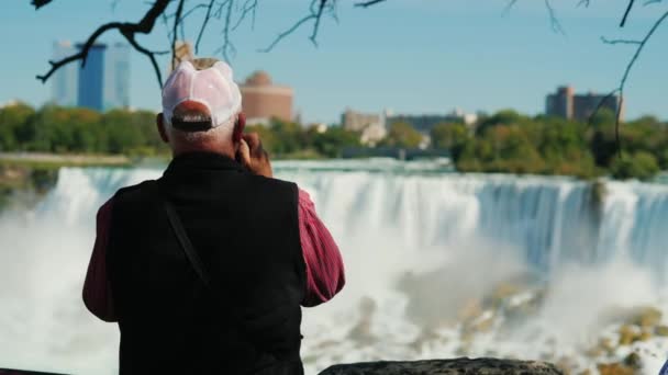 Un homme âgé prend des photos des célèbres chutes du Niagara. Vue de derrière. Concept de personnes matures actives — Video