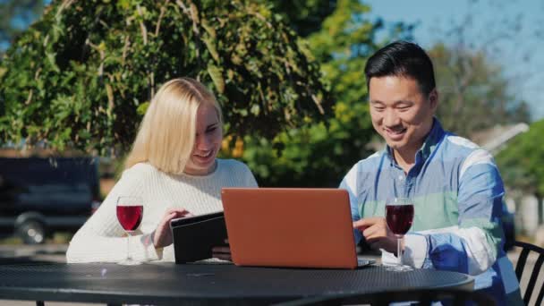 Asiatisk man och kaukasisk kvinna avkopplande i café. Användning laptop och tablett — Stockvideo