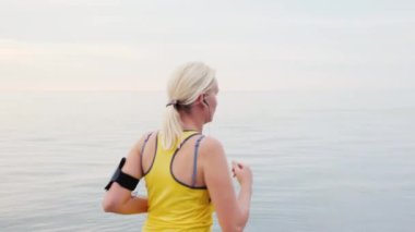 Atış Steadicam: genç kadın deniz veya göl, dikiz arka plan üzerinde koşu. Yan görünüm