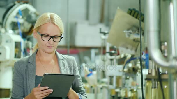 Eine Frau im Anzug arbeitet mit dem Tablet in einem Raum für eine Weinproduktionsanlage — Stockvideo