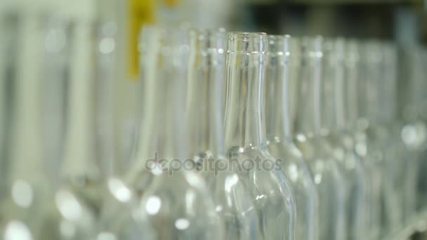 Varias botellas vacías para bebidas alcohólicas en el transportador. Muévete lentamente a lo largo de la cinta — Vídeos de Stock