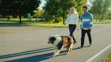 Asyalı erkek ve beyaz kadın köpeğini ile parkta yürüyüş