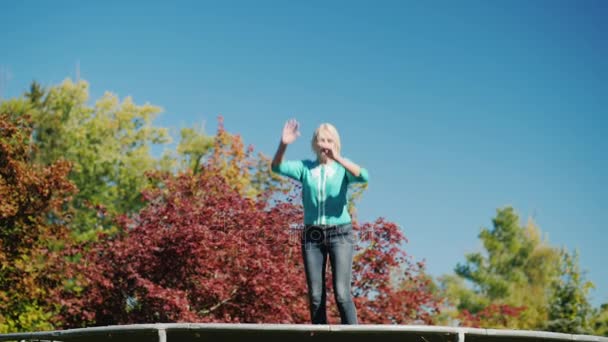 Aktiv livsstil. En medelålders kvinna hoppar högt på en studsmatta. Mot himlen — Stockvideo
