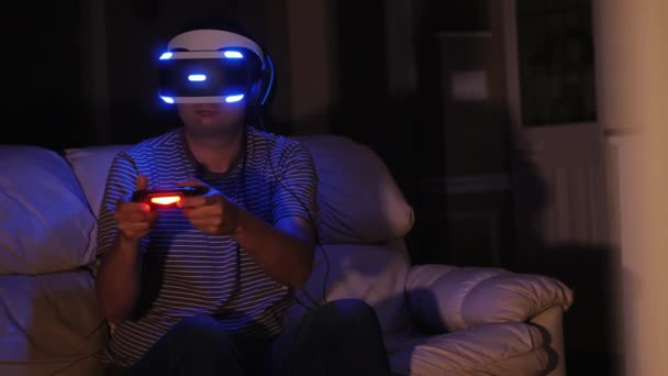 Un hombre de mediana edad juega juegos de ordenador en el casco de la realidad virtual. Tarde en la noche, adicción al juego — Vídeo de stock