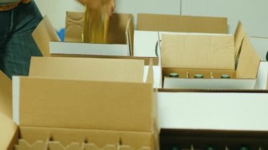 İki işçi şarap şarap şişeleri kutulara koydum. Tüketiciler için sevkıyat için hazırlanıyor