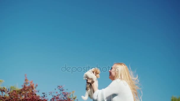 Femme blonde rebondit haut contre le ciel, tient un chiot dans ses mains. Vidéo 4K — Video