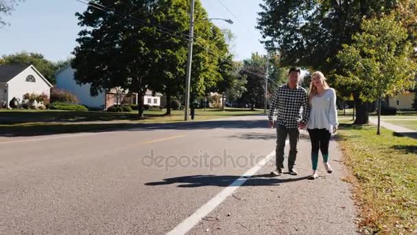 Junges Paar, das Händchen haltend die Straße hinuntergeht. typisch amerikanische Stadt — Stockvideo