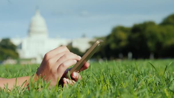 Kezében egy smartphone. A gyepen, a háttérben a Capitol, Washington. Utazási és dolgozószoba-ban az USA-ban koncepció — Stock videók