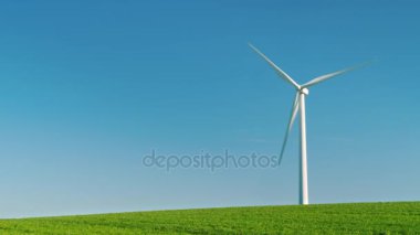 Endüstriyel Rüzgar jeneratörü yeşil bir tepede duruyor. Mavi gökyüzü, saf enerji idylistic bir resmi arka planı