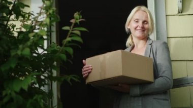 Porter bir parsel onun elinde olan bir kadın. Kameraya bulmak için evine in üzerindedir. Düşük gelirli aile