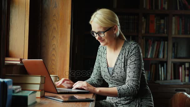 Zakenvrouw werken met de laptop. Zit bij het raam in het kantoor — Stockvideo