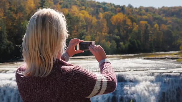 Eine Frau fotografiert einen Wasserfall im letchworth State Park. — Stockvideo