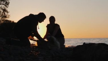 Arkadaşlar Gölü yakınındaki bir köpekle oynuyorlar. Gün batımında