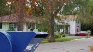 Bir kadının kollarında bir köpekle bir posta kutusu sokakta yaklaşımlar ve bir mektup içine atar