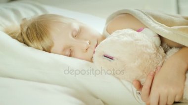 Onu evde beslenen hayvan oyuncak ile yatakta uyuyan küçük kız