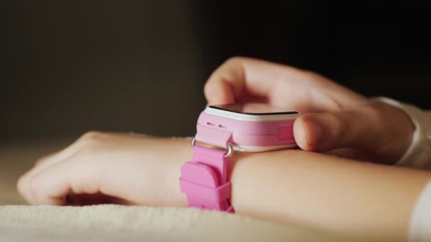 Primer plano de una mano de niño con un reloj inteligente rosa — Vídeos de Stock