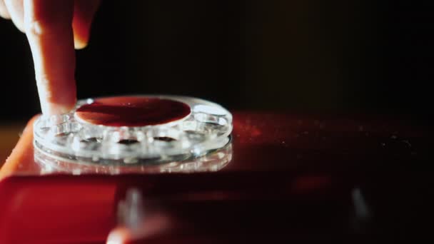 Женская рука набирает номер на диске старого ретро-телефона в красном — стоковое видео