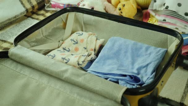 Mutter und Tochter machen Urlaub. zwei Hände legen Dinge und Spielzeug in eine Reisetasche. — Stockvideo