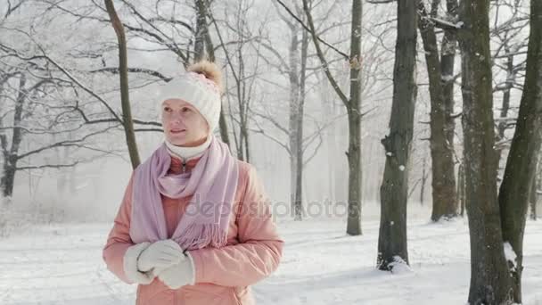 一个穿着粉红色夹克的女人在冬天的公园里散步。它在下雪, 一个美丽晴朗的日子 — 图库视频影像