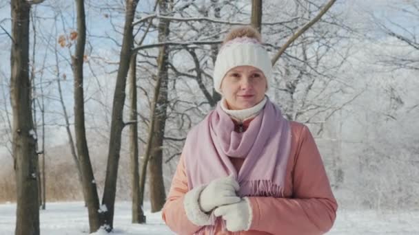 Eine glückliche junge Frau geht im Winterwald spazieren. ein schöner klarer Tag, die Zweige der Bäume sind mit Raureif bedeckt — Stockvideo