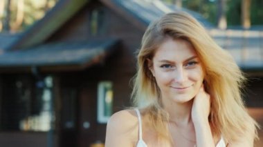 Genç kadın ile anahtar taşı--dan ev. Gülümseyen, kameraya bakıyor. Arka planda yeni ahşap yazlık