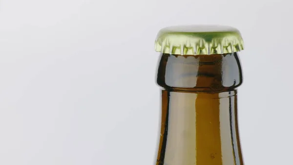 一瓶啤酒的脖子上盖着一个金属盖子。在白色背景 — 图库照片