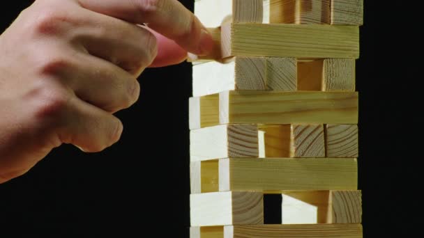 Two people take turns pulling out wooden bars from the tower. Playing in Jenga — Stock Video