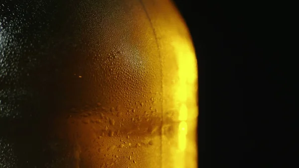 Uma garrafa de cerveja gelada com gotas de água. Em um fundo preto . — Fotografia de Stock