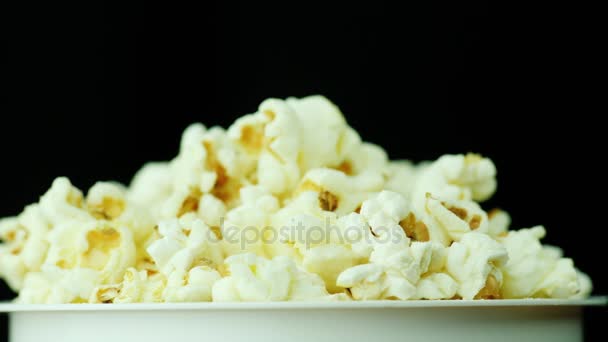 Ein Glas Popcorn auf schwarzem Hintergrund. dreht sich langsam — Stockvideo