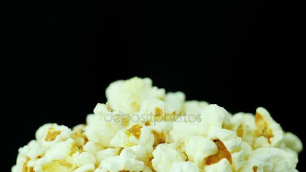 Een stelletje popcorn op een zwarte achtergrond. Langzaam draait — Stockvideo