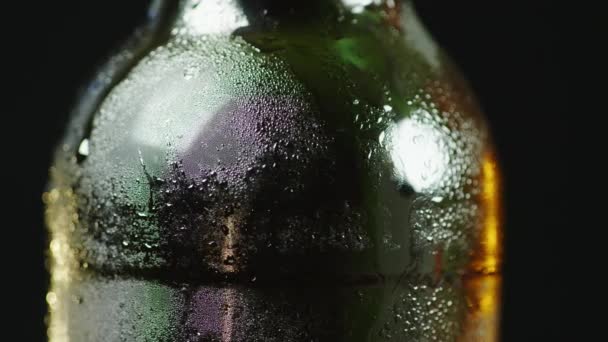 Szklana butelka zimnego piwa. Krople pojawił się na powierzchni. Na czarnym tle. — Wideo stockowe