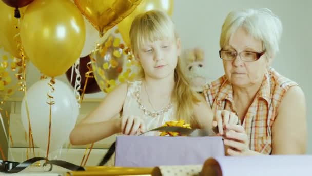Бабушка и внучка собирают подарки вместе. Концепция активных пожилых людей — стоковое видео
