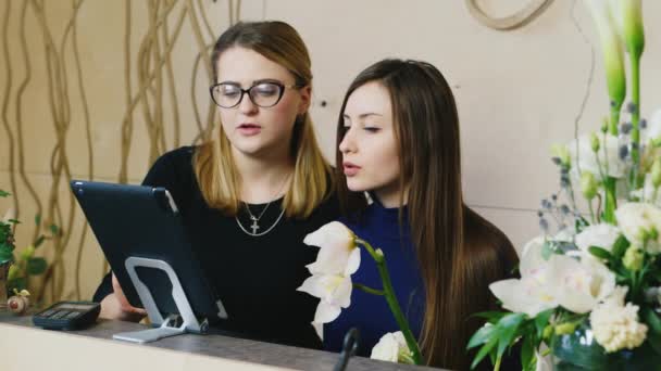 Duas jovens trabalhando com o tablet em uma loja de flores — Vídeo de Stock