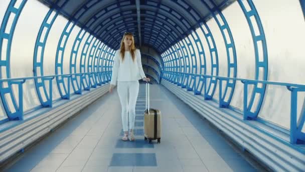 Joven mujer de negocios con bolsa de viaje sobre ruedas está en la transición desde la terminal en el aeropuerto o estación de tren — Vídeo de stock