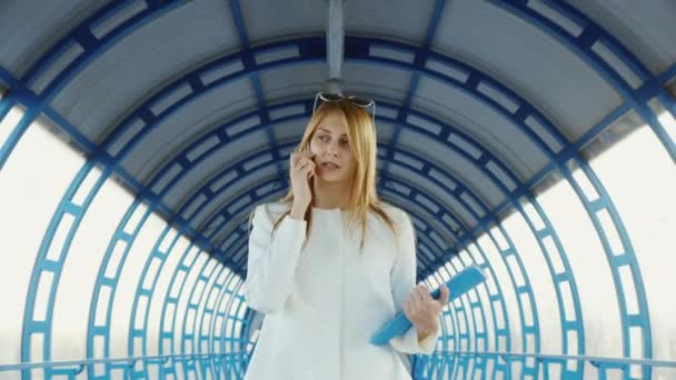 Бізнес-леді говорить по телефону. Швидко проходить через скляний тунель у бізнес-центрі — стокове відео