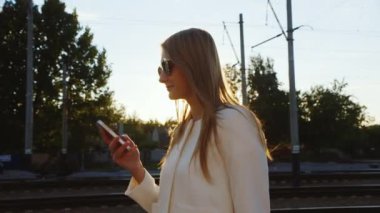 Tren istasyonu platformu yürüyen çekici kadın telefon kullanır