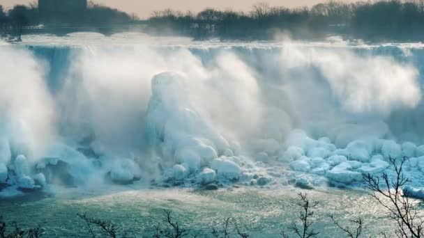 Знаменитый Ниагарский водопад зимой. Вода падает на камни, покрытые льдом и снегом. Вид с канадского побережья — стоковое видео