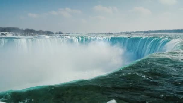 Epikus jelenet Niagara Falls. A vízesés, az alakja egy patkó, jég floes úszó a víz mentén. Turizmus-tél koncepció — Stock videók