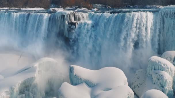 Průtok vody z Niagara řeka padá na kameny, pokryté sněhem a ledem. Úžasné zimní scéna u Niagarských vodopádů. 4 k video zpomaleně — Stock video