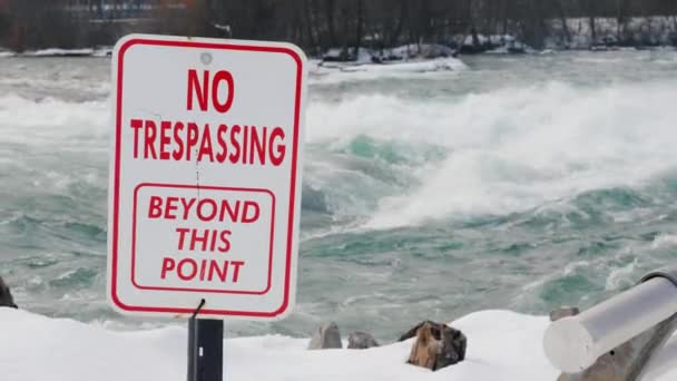 Una targa con un'iscrizione "Nessuna violazione di domicilio". Pericoloso per il nuoto e per il luogo di vita. Sullo sfondo scorre l'acqua tempestosa del fiume. Fiume Niagara di fronte alle cascate del Niagara — Video Stock