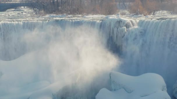 ナイアガラの滝で冬の季節。水の流れは、氷と雪で覆われた石に落ちる。4 k スローモーション ビデオ — ストック動画