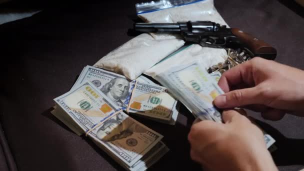 Las manos de los hombres cuentan el dinero en el fondo de las armas y paquetes de drogas. Dinero sucio y concepto de tráfico de drogas — Vídeos de Stock