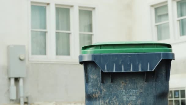 Un uomo getta un sacco di spazzatura in un serbatoio di plastica vicino a casa sua. Rimozione e trasformazione del concetto di spazzatura — Video Stock