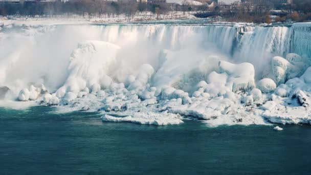 Το παγωμένο καταρράκτες του Νιαγάρα. Ροές του νερού πέσει στα βράχια που καλύπτονται με τον πάγο. Φύση ΗΠΑ και τον Καναδά το χειμώνα — Αρχείο Βίντεο