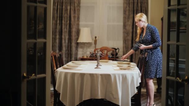 Faltet die junge Hausfrau das Geschirr auf. serviert den Tisch zum Abendessen — Stockvideo