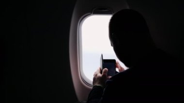 Pencereden dışarı bakan bir uçağın penceresinden fotoğraf çekmek birisi silüeti