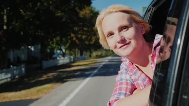 Een vrouw is reizen in een auto, gluren uit het raam voor onderweg. Slow motion video — Stockvideo